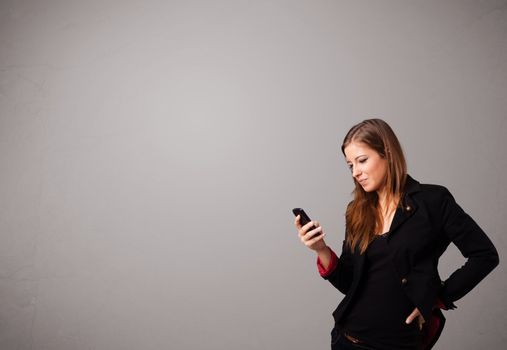 attractive young lady standing and holding a phone with copy space