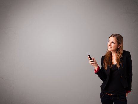 attractive young lady standing and holding a phone with copy space