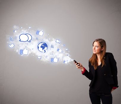 Pretty young girl holding a phone with social media icons in abstract cloud