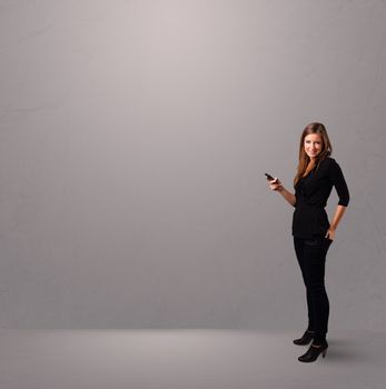 attractive young lady standing and holding a phone with copy space