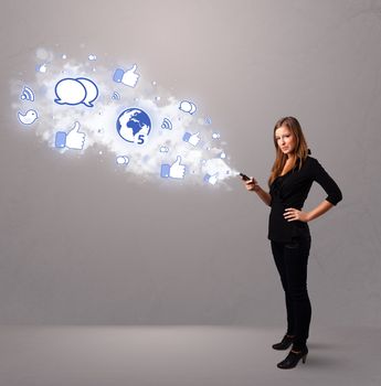 Pretty young girl holding a phone with social media icons in abstract cloud