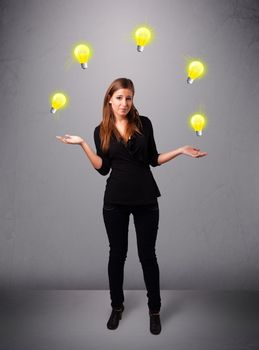 beautiful young lady standing and juggling with light bulbs