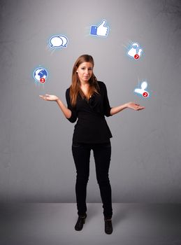 attractive young woman standing and juggling with social network icons