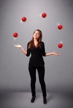 pretty young girl standing and juggling with red balls
