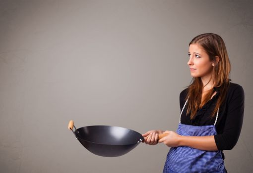 Attractive young lady holding a frying pan