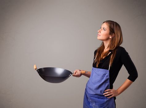 Attractive young lady holding a frying pan