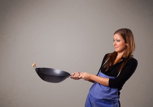 Attractive young lady holding a frying pan