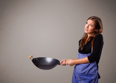 Attractive young lady holding a frying pan
