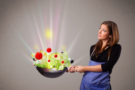 Beautiful young woman cooking fresh vegetables with abstract lights