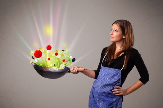 Beautiful young woman cooking fresh vegetables with abstract lights