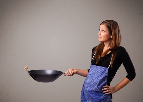 Attractive young lady holding a frying pan