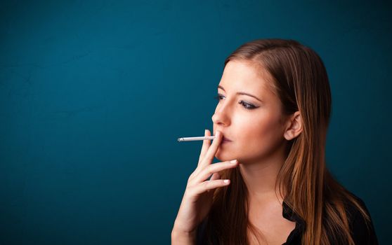 Beautiful young woman smoking cigarette with copy space