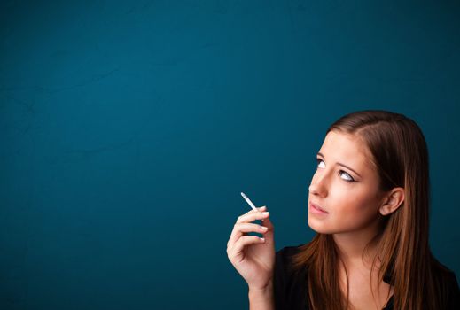 Beautiful young woman smoking cigarette with copy space
