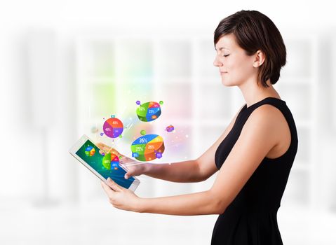 Young business woman looking at modern tablet with colourful pie charts