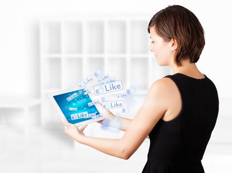 Young business woman looking at modern tablet with social icons