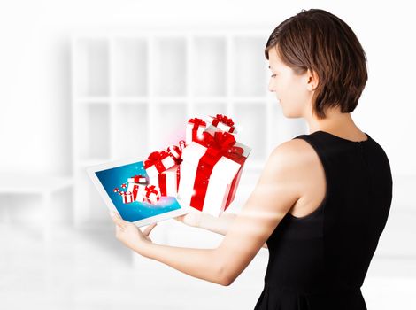 Young business woman looking at modern tablet with present boxes