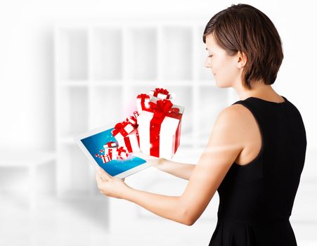 Young business woman looking at modern tablet with present boxes