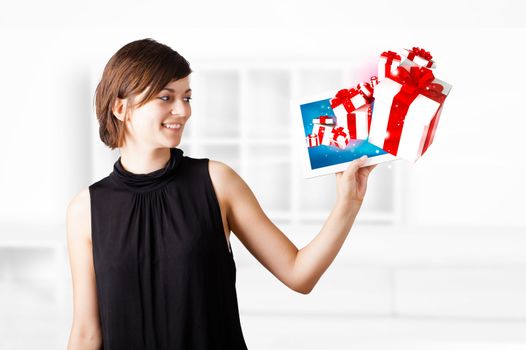 Young business woman looking at modern tablet with present boxes