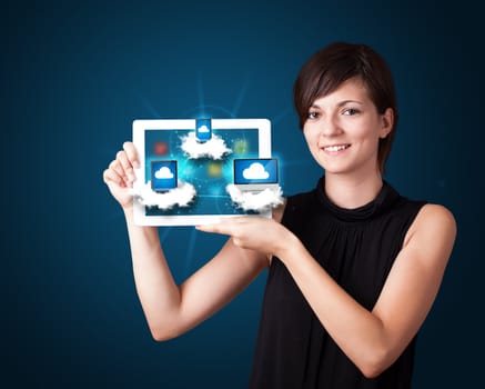 Beautiful young woman holding tablet with modern devices in clouds