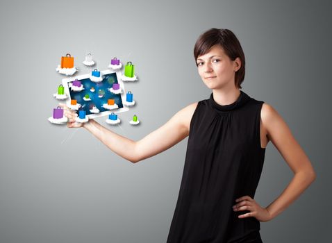 beautiful woman holding modern tablet with colorful shopping bags on clouds