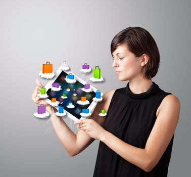 beautiful woman holding modern tablet with colorful shopping bags on clouds