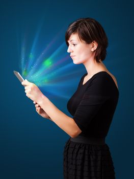 Young business woman looking at modern tablet with abstract lights 