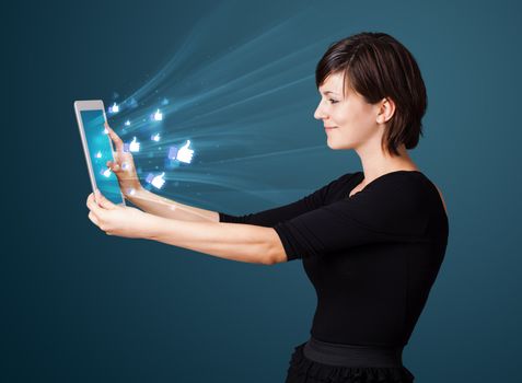 Young business woman looking at modern tablet with abstract lights and social icons