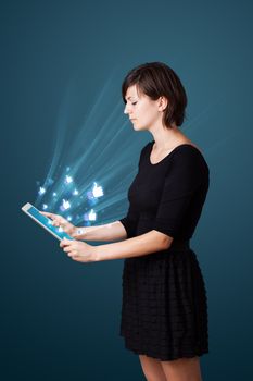 Young business woman looking at modern tablet with abstract lights and social icons