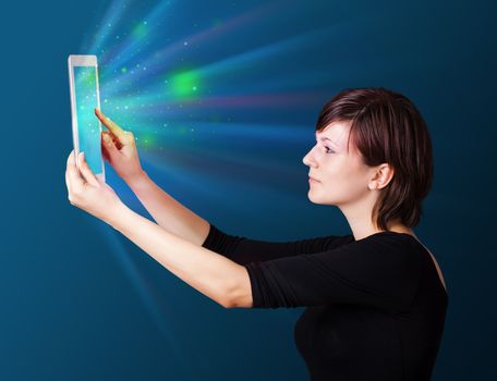 Young business woman looking at modern tablet with abstract lights 