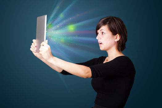 Young business woman looking at modern tablet with abstract lights 