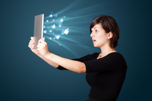 Young business woman looking at modern tablet with abstract lights and social icons