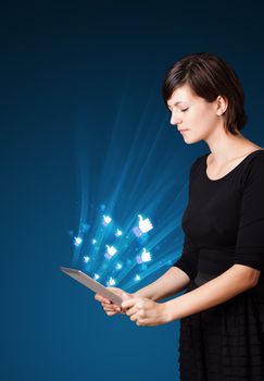 Young business woman looking at modern tablet with abstract lights and social icons