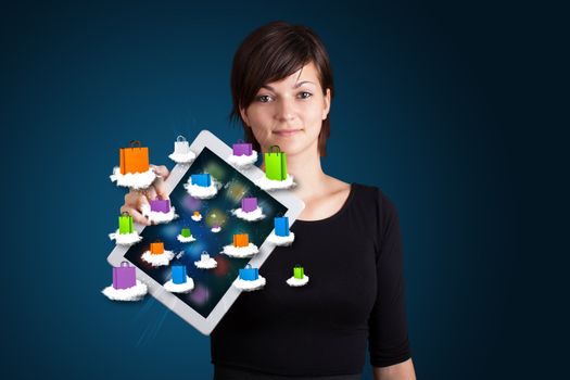 beautiful woman holding modern tablet with colorful shopping bags on clouds