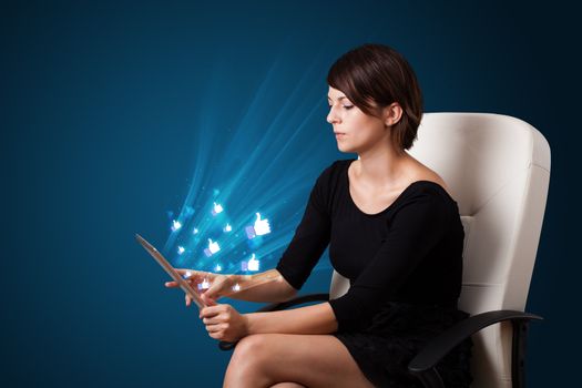 Young business woman looking at modern tablet with abstract lights and social icons