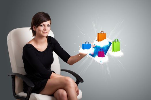 beautiful woman holding modern tablet with colorful shopping bags on clouds