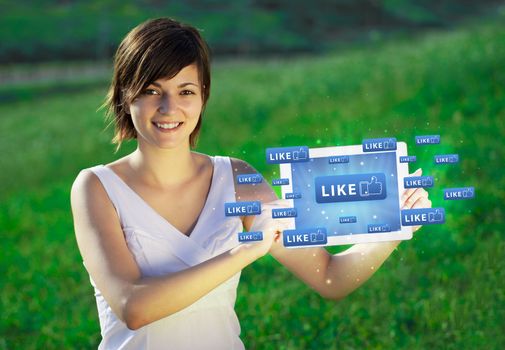 Young business woman looking at modern tablet with abstract lights and social icons