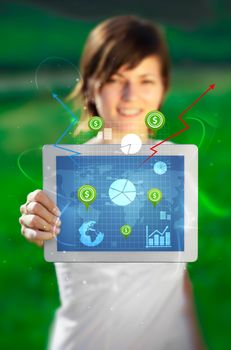 Young business woman looking at modern tablet with abstract light and various diagrams