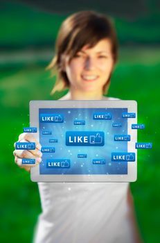 Young business woman looking at modern tablet with abstract lights and social icons