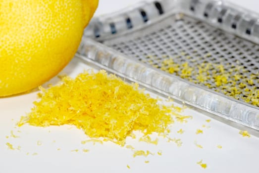 Small heap of grated lemon zest with a whole lemon and grater