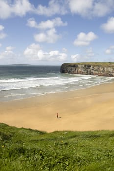 Beautiful view over the Ballybunion beach and cliffs on the Atlantic coast in Ireland with solitary man