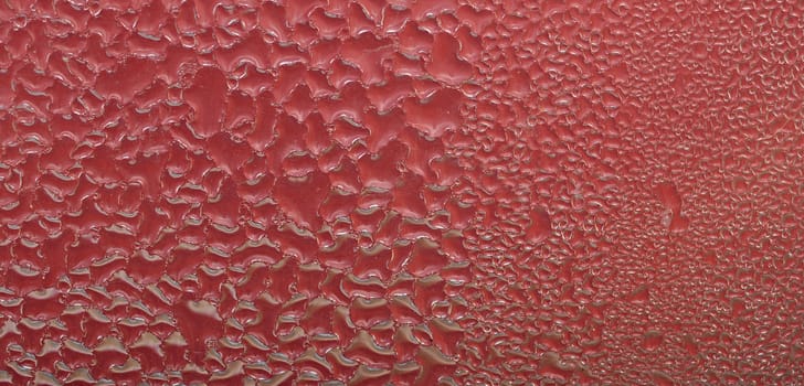 Water drops on abstract red surface.