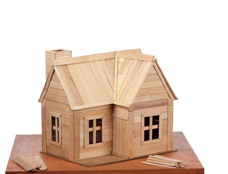 A completed popsicle stick house is displayed with some unused building material.