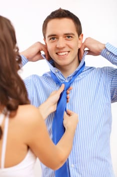 Young businessman dressing at home in the morning. Woman helping to fasten his tie