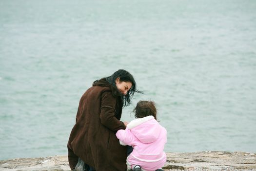 Back view of mother and daughter in beautiful spring sea