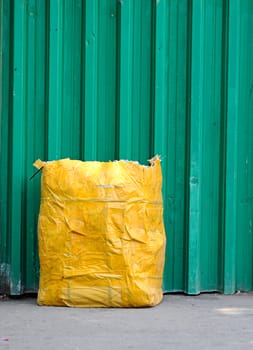 yellow garbage bag  front green fence