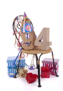 Number of age in a colorful studio setting with paper party hat and figures, a red heart and gifts