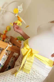 Pregnant woman tummy decorated with yellow ribbon and bow 