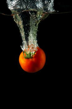 fresh tomato uder water on black background