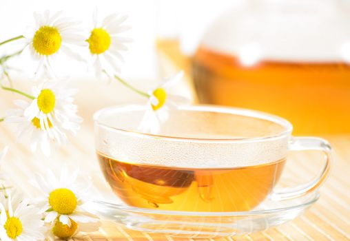 A teacup and a teapot with herbal chamomile tea