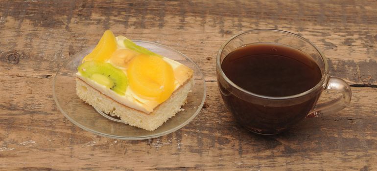 Close-up of glass cup of coffee and apricot cake on wooden table